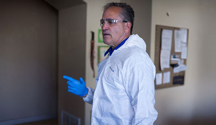 Inspector wearing white hazmat suit and blue gloves