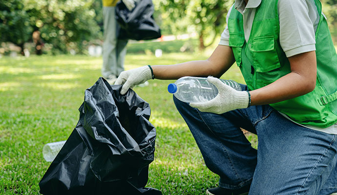 Volunteer collecting plastic bottles in park