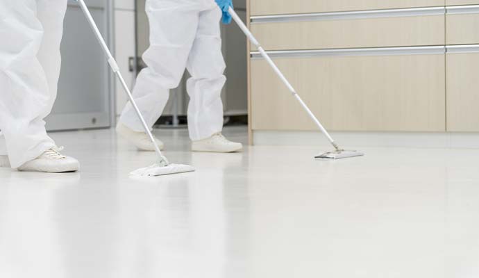 Cleaning crew in protective suits mopping floor