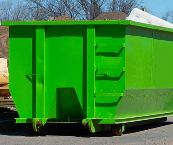 A large, bright green industrial roll-off dumpster filled with debris