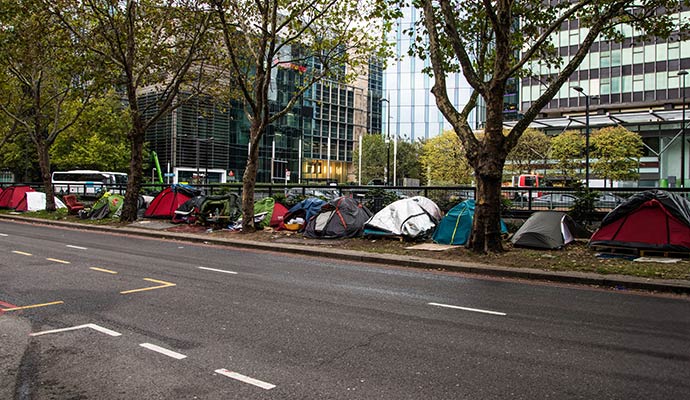 A line of temporary encampment positioned along a sidewalk