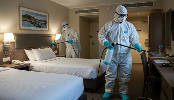 Experts in protective gear disinfecting a hotel room during infectious disease cleanup