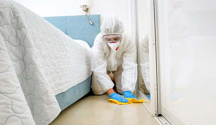 Professionals performing infectious disease cleanup service in a bedroom