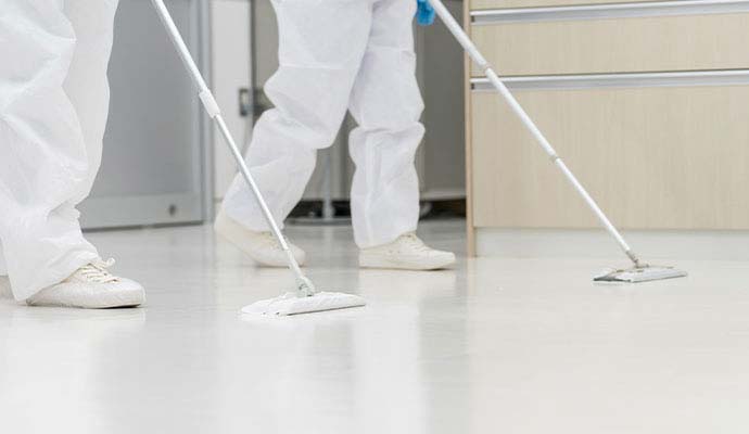 Two experts sanitizing a floor after industrial trauma cleanup