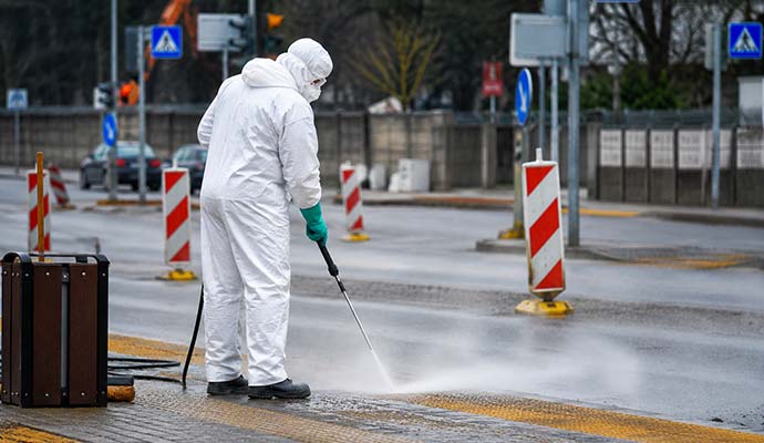 Professionals in hazmat suits cleaning up a blood spill on a sidewalk