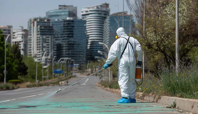Expert in protective gear performing street decontamination service