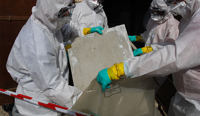 Professional team carefully placing a contaminated floor tile into a specialized disposal bag