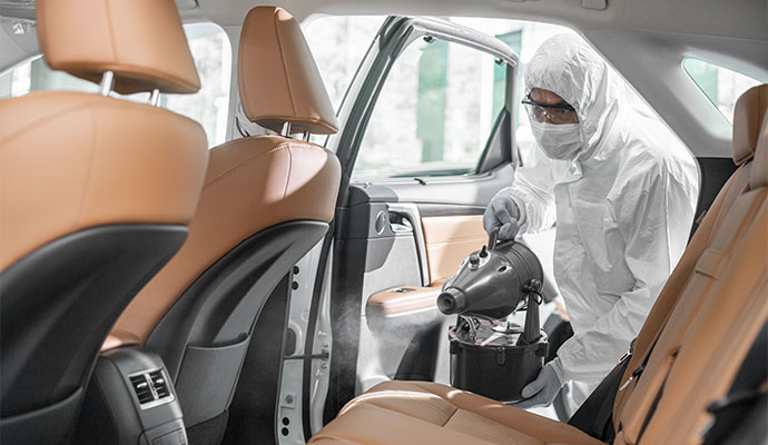 Professional worker sanitizing car interior
