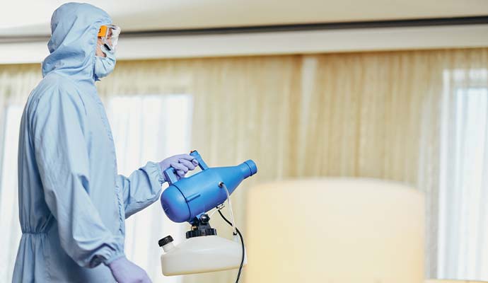 Technician in protective suit operating fogger machine