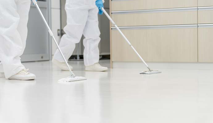 Technicians in protective suits mopping floor