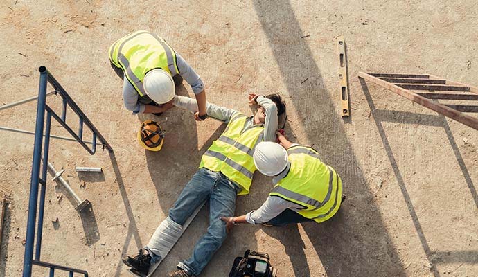 Construction workers attending injured worker on ground