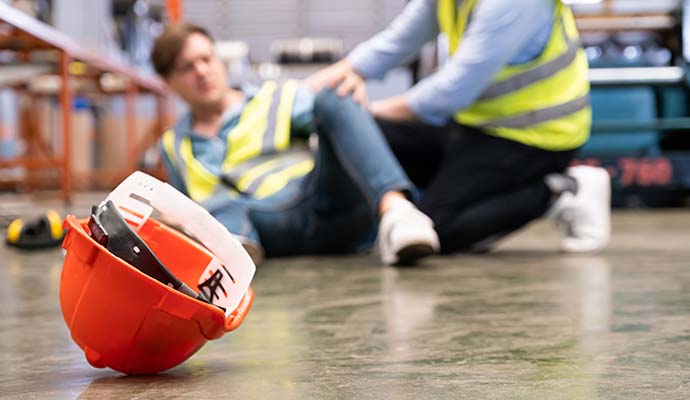 Fallen hardhat on floor with injured worker in background