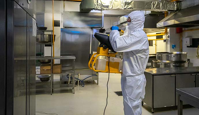 Worker in protective suit fogging commercial facility