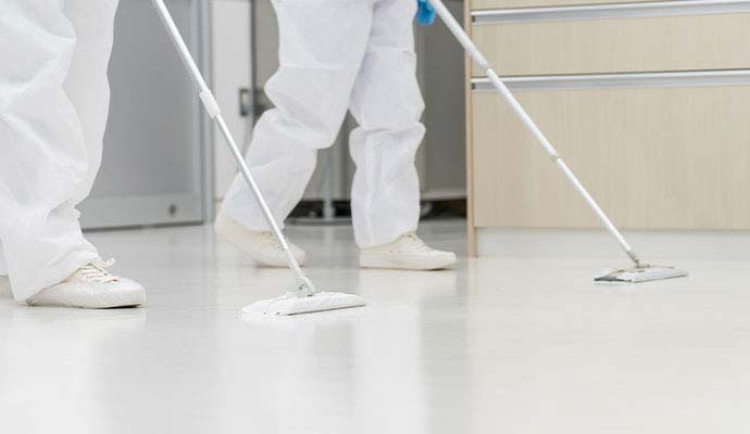 Workers in protective suits mopping commercial floor
