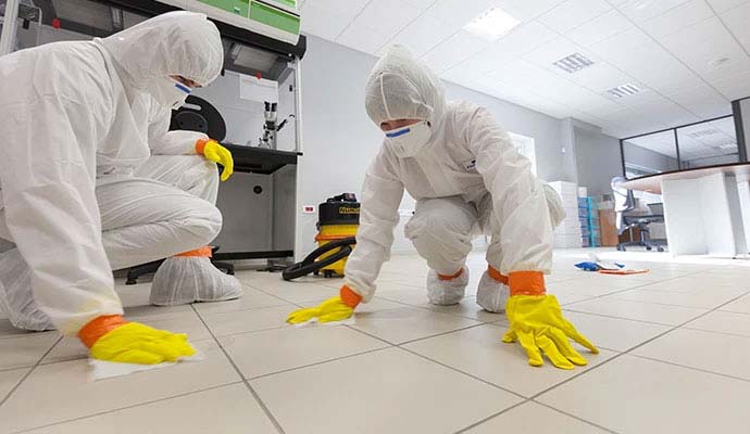 Professionals in hazmat suits cleaning up a workplace accident
