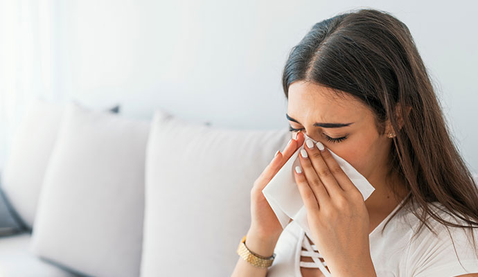 A young woman sneezing into tissue
